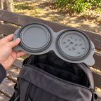 The double bowl folded flat in one hand above a backpack