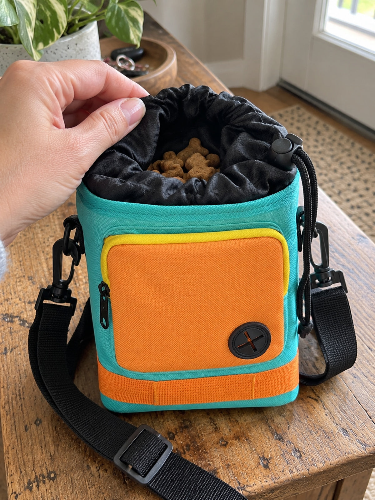 Opening the drawstring top of the treat pouch to show treats inside